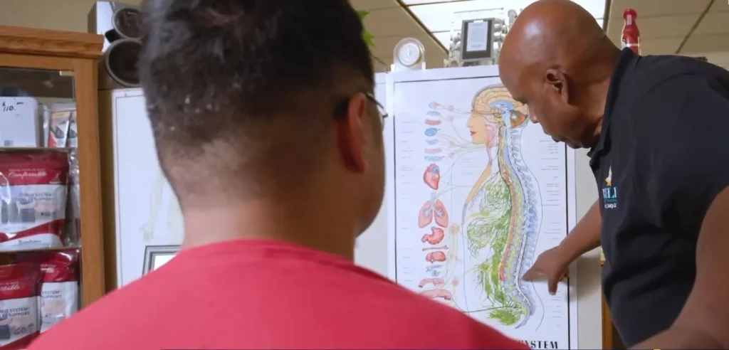 Dr. Bell explaining the spine to a patient using an anatomy chart