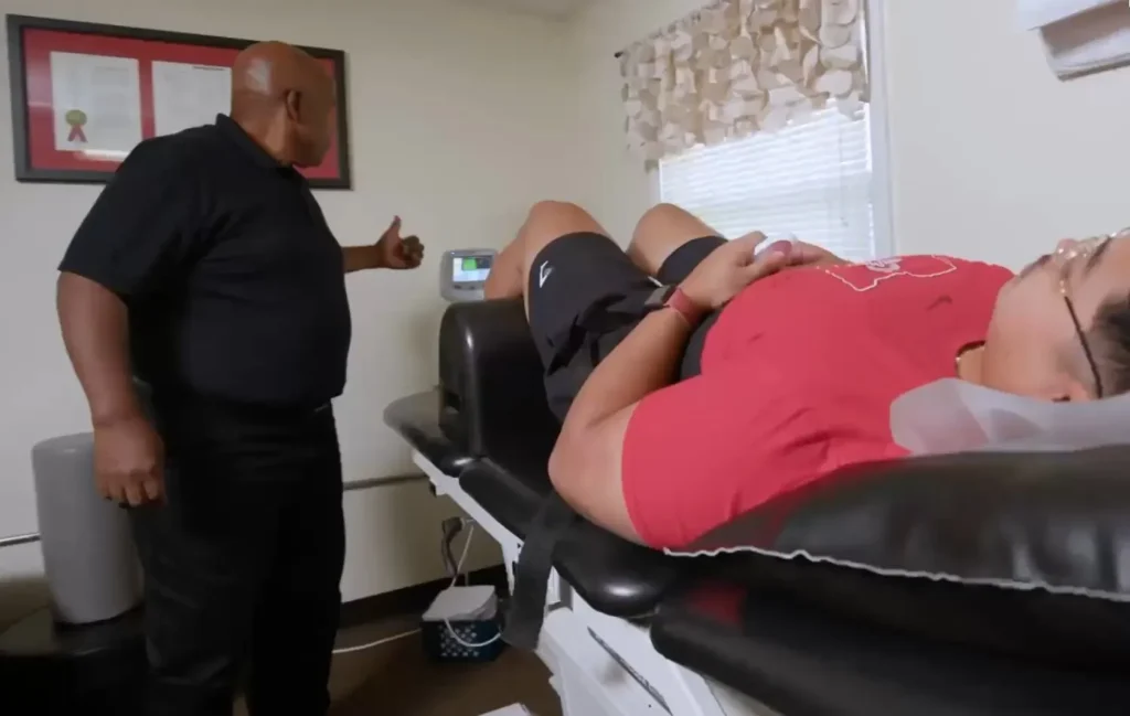 Patient on the cervical and lumbar decompression table while Dr. Bell explains the treatment